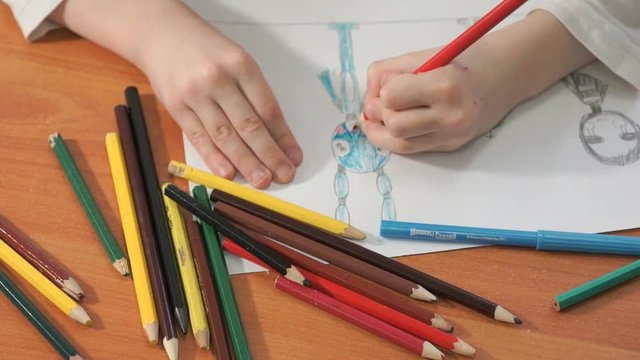 Close-up of unknown child draws the pictures using color pencils in the album in the kindergarten