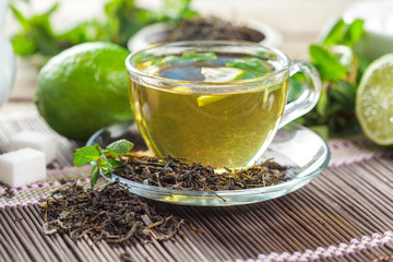 cup of black tea with mint leaves on a wooden table