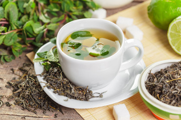 cup of black tea with mint leaves on a wooden table