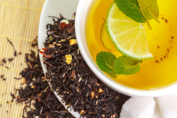 cup of black tea with mint leaves on a wooden table
