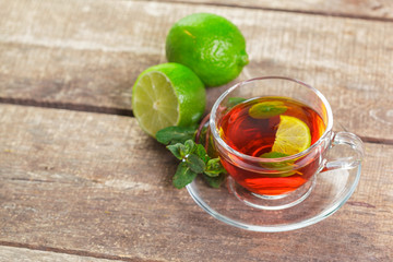 cup of black tea with mint leaves on a wooden table