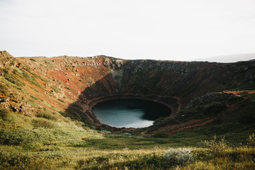 beautiful kerid volcanic lake and green vegetation on rocky hills in iceland