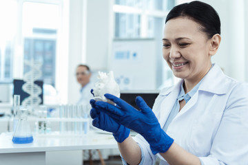 Laboratory work. Beautiful inspired experienced scientist holding an experimental unit and working a uniform while working in the lab