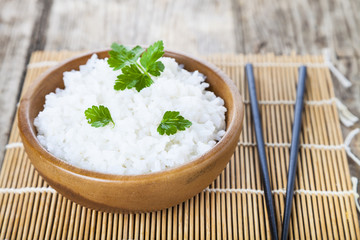 Boiled rice in a wooden bowl and chopsticks