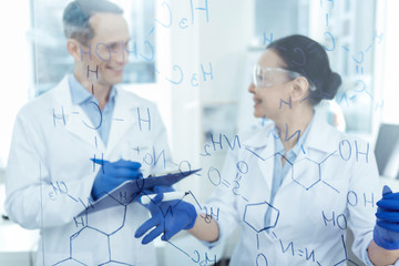 Wonderful breakthrough. Good-looking cheerful smart experienced scientists smiling and writing formulas and discussing their research