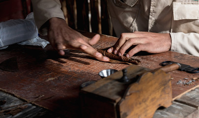 Close-up of hands wrapped from the dry tobacco leaves of a true Cuban cigar.