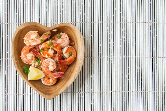Top view of delicious cooked prawns with slice of lemon and fresh finely cut parsley. Appetizing, protein-rich, diet and balanced meal. Copy space in right side