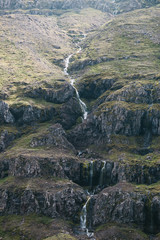 beautiful landscape with small waterfall on rocky slope in iceland