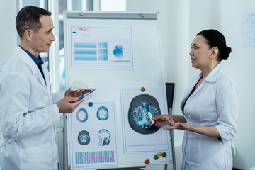 Brainstorming. Professional scientists looking at brain image while discussing aneurysm