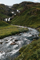 beautiful scenic icelandic landscape with majestic waterfall and green hills, Eastern Iceland