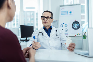 Medical world. Professional doctor sitting at the table and talking to her patient
