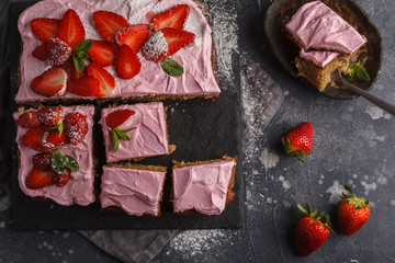 Yogurt pound cake for breakfast with pink glaze and fresh strawberries. Dark background, summer berry dessert. Top view, copy space.