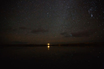 Illuminated building reflected in water and spectacular starry sky at night, Iceland