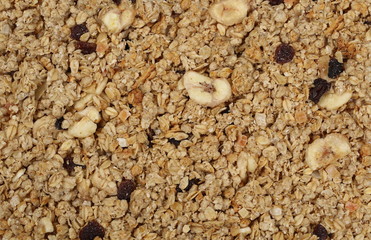 Crunchy granola, muesli pile with banana, pineapple slices, peanuts and raisins background and texture