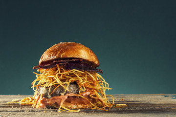 Home made hamburger with lettuce and cheese on board.