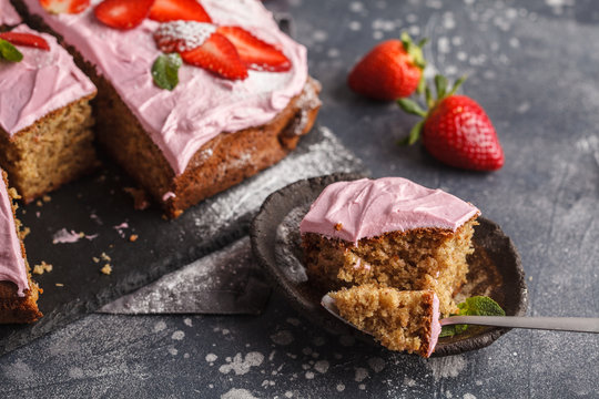 Piece of yogurt pound cake for breakfast with pink glaze and fresh strawberries. Dark background, summer berry dessert, copy space.