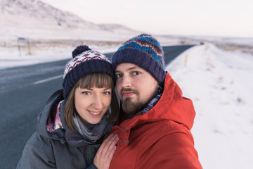 Fototapeta na wymiar beautiful young couple looking at camera while standing near asphalt road in iceland