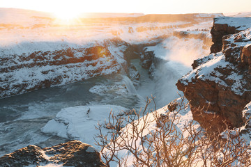 spectacular view of beautiful Gullfoss waterfall and snow-covered rocks at sunrise, iceland