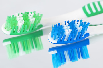 Toothbrushes on a mirrored surface.