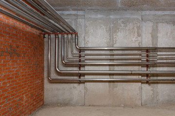 Metal pipes on the background of the joint of brick and concrete walls.