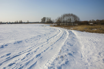 Fototapeta na wymiar Winding snowy road in field and grove