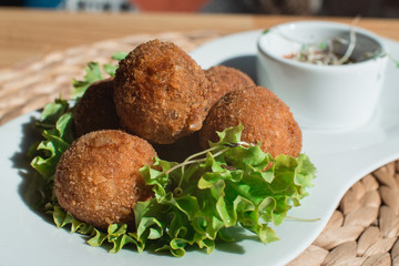 closeup of plate with spanish croquettes served with salad and sauce