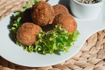 closeup of plate with spanish croquettes served with salad and sauce