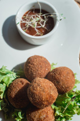 closeup of plate with spanish croquettes served with salad and sauce
