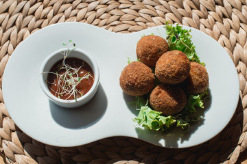 closeup of plate with spanish croquettes served with salad and sauce