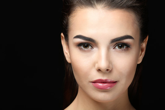 Young woman with beautiful eyebrows on black background