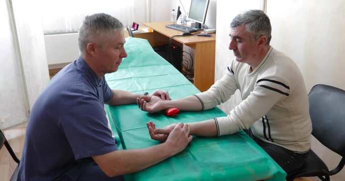doctor treats the man of the patient with Chinese medicine. Patient shows the doctor his tongue
