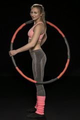 athletic woman holding hula hoop in her hands, isolated on the black background