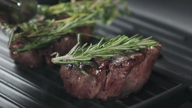 Slow motion slide shot of preparing steak filet mignon with butter and herbs