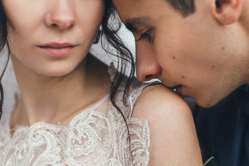 Groom kisses bride's shoulder standing outside