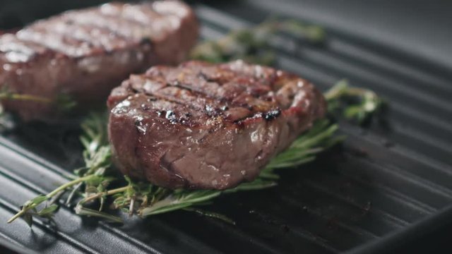 Slow motion slide shot of preparing steak filet mignon with butter and herbs