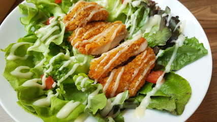 Breaded fried chicken with organic green caesar salad tomato on wooden table at western restaurant, food recipe menu advertisement