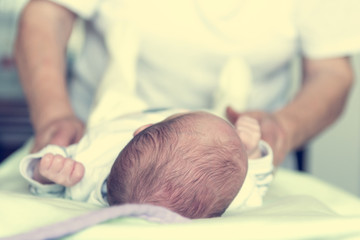 Closeup of newborn baby holding elderly hands.
