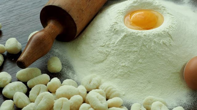 Raw potato gnocchi with eggs, flour and rolling pin on a wooden table