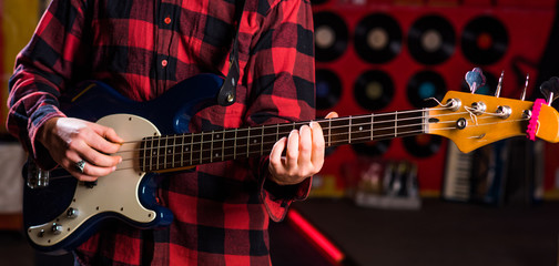 Fototapeta premium Male hands hold guitar, play music in club atmosphere background.