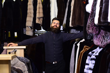 Guy with smiling face in front of coats on background.