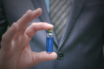 Blue pill essential oil in male hands. Presentation of new drug pill or steroid concept. Right...