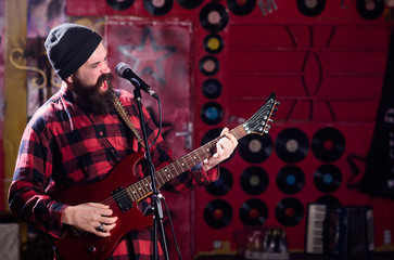 Musician with beard play electric guitar instrument.