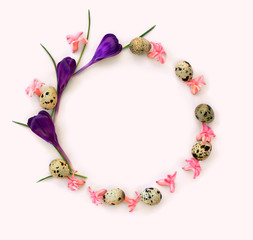 Circle spring frame of pink flowers hyacinth, violet crocuses and quail eggs on light pink background with space for text. Top view, flat lay