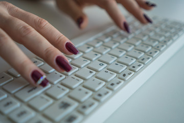 A woman is typing a message on a computer keyboard close-up