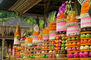 Traditional Balinese ceremonial temple offerings: big fruits and rice pyramids on golden plates...