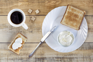 Composition with butter coffee and toasts on wooden table