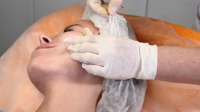 Healtcare clinic. Young female client gets thread face lifting procedure. Beautician in gloves making face anti-aging to a female face