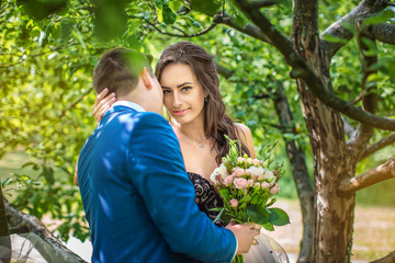 Obraz premium Groom kisses on cheek happy bride in park. Newlyweds