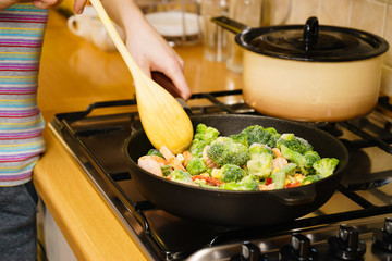 Girl frying vegetables on pan