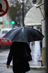 Woman in rain walking with umbrella.